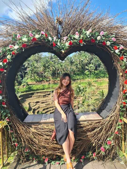 Jee posing in a heart-shaped floral structure in Bali